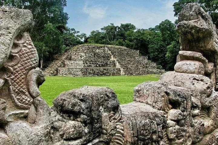 Steinreliefs, die eine entfernte Stufenpyramide in den Copán Ruinen einrahmen