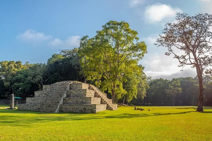 A small stepped pyramid structure surrounded by trees at Copan Ruins