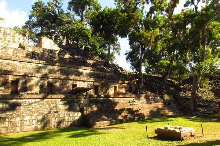 Stone ruins with small square doorways built into a hillside at Copan Ruins